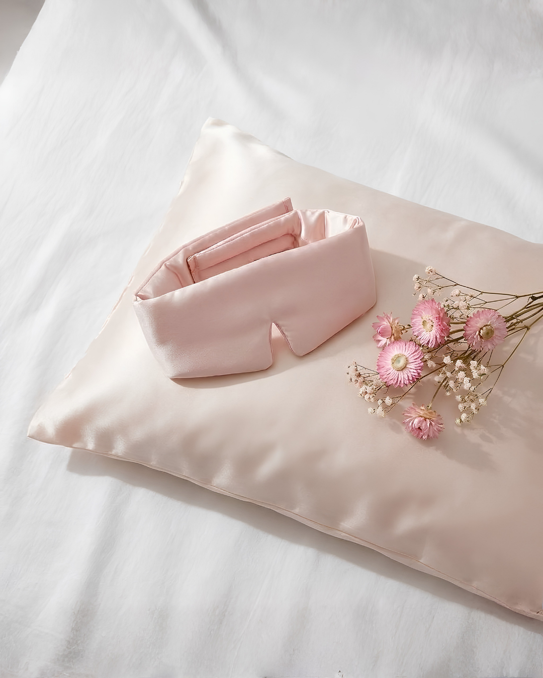 Antifaz de satén rosa sobre una almohada rosa